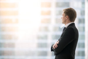 Photo of a business professional looking out a high-rise window.