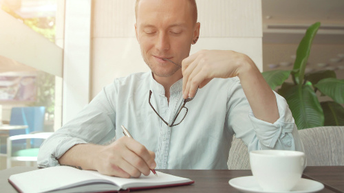 Photo of a man writing out his dating criteria.