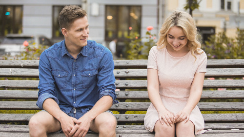 Photo of a couple sitting on a bench together.