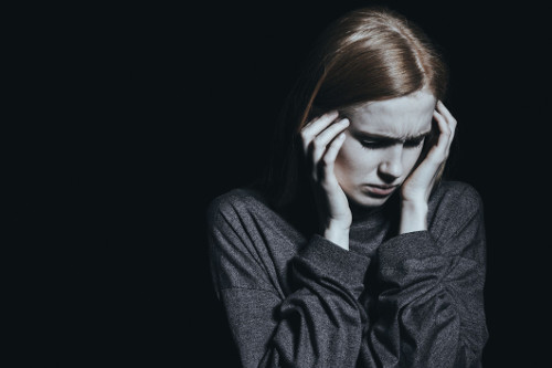 Image of woman in need of PTSD treatment holding her head