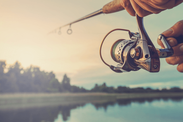 Image of someone holding a fishing pole that is cast out into water